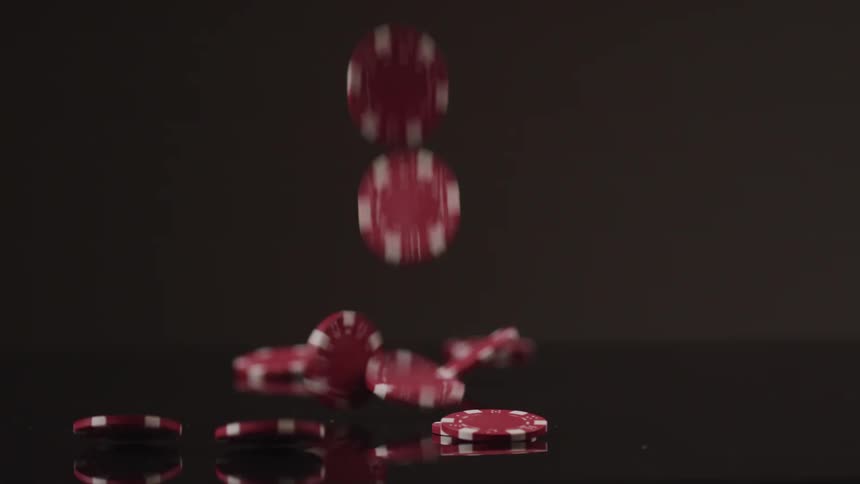 Red poker chips fall and bounce on the black surface