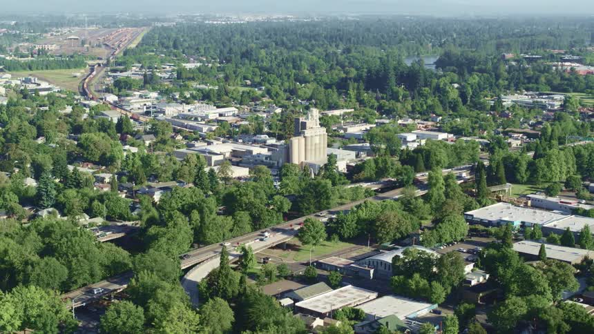 Traffic winds along highway cutting through forest and town