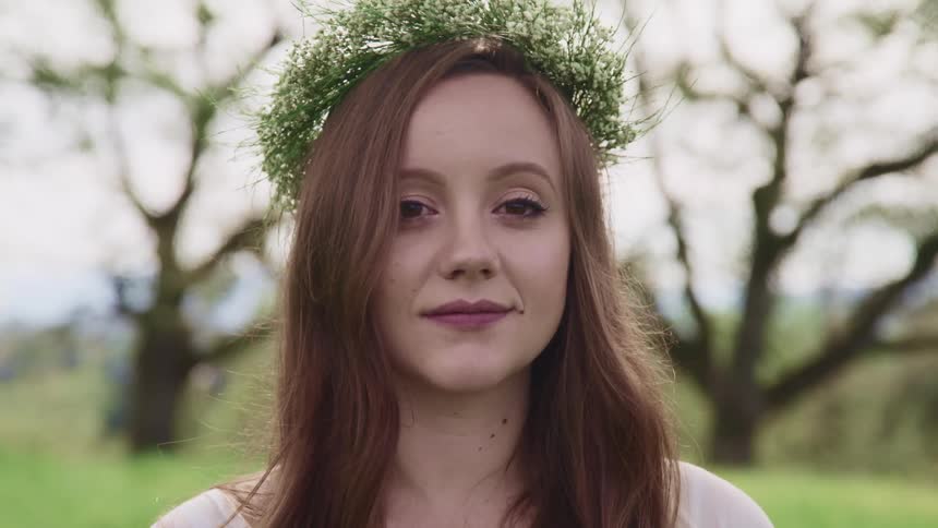 Close up of the face of a long haired woman with a wreath on her head