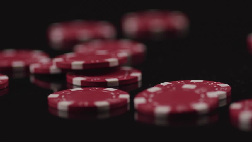 Red and white poker chips piled on a black surface