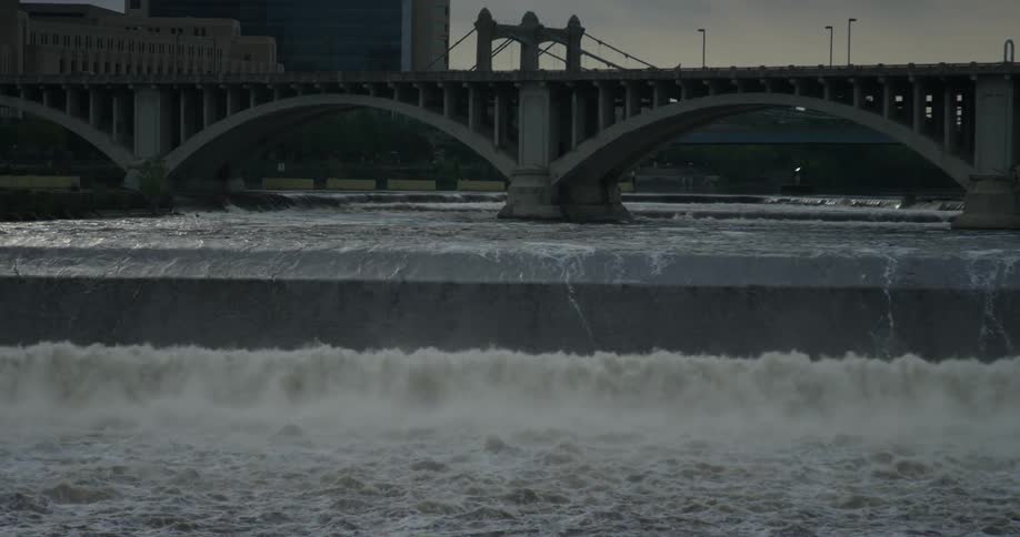 Water goes under bridge and over a short waterfall