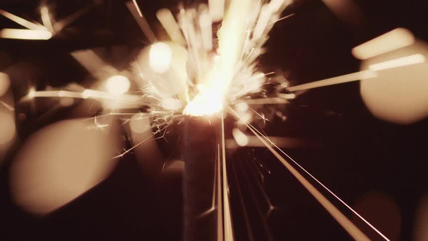 Firework sparkler burns sending sparks into darkness