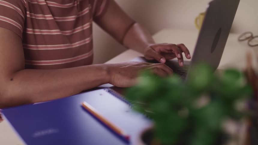 Female sitting at desk typing on laptop that is next to a notebook and pencil