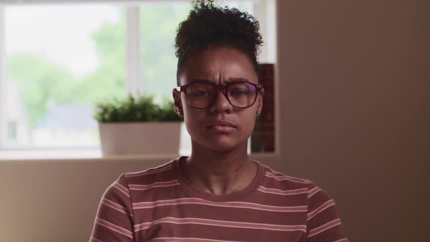 Woman wearing glasses sits backed by window nods as she talks