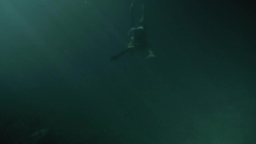 Swimmer holds a weapon while swimming underwater