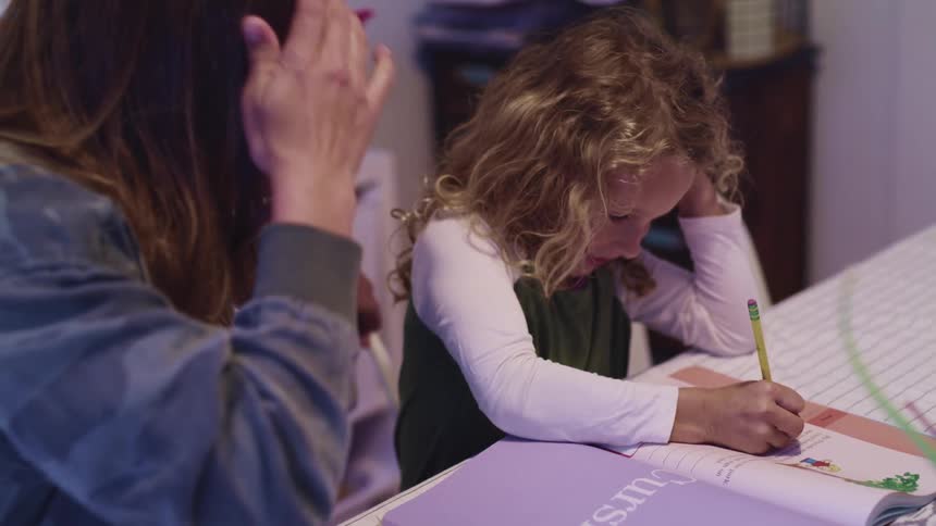 Mother helps daughter with homework at home