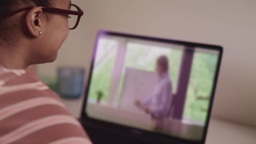 Young woman attends an online class on her laptop at home
