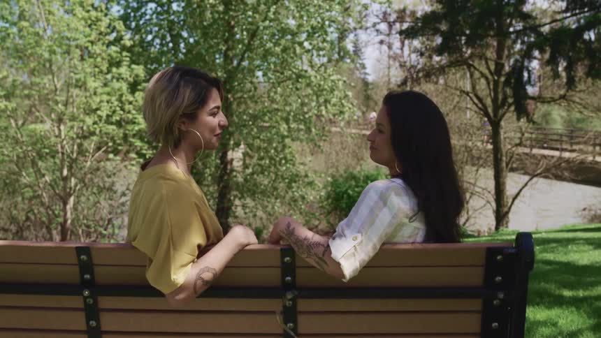 Two woman sitting on a park bench talking