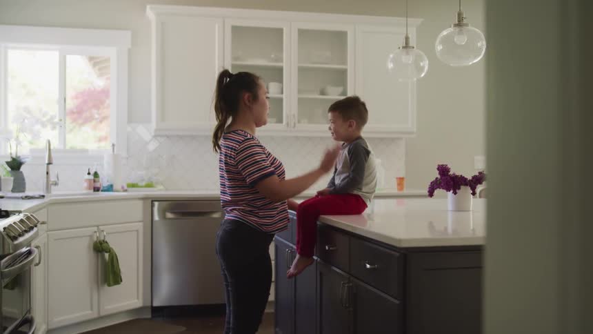 Mother playing with son in the kitchen at home