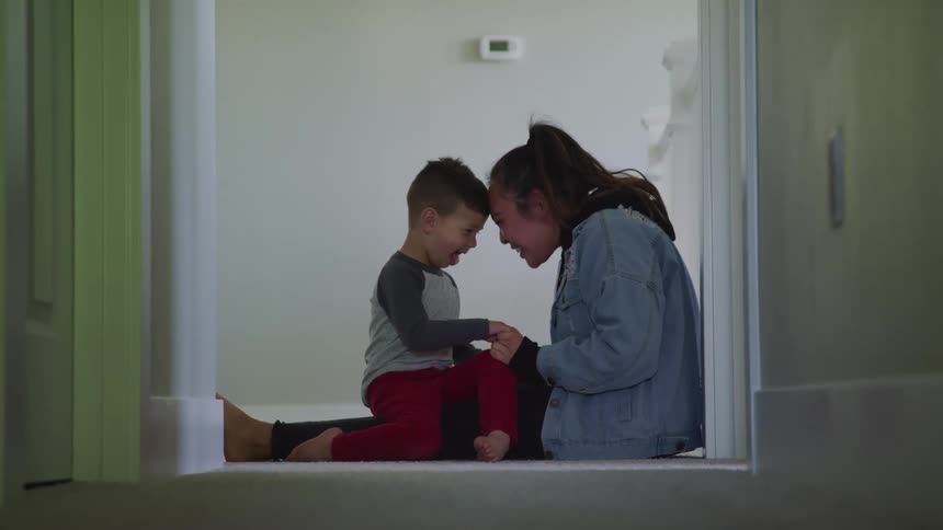A little boy sits on a teenagers knee and they talk
