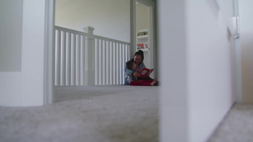 Mother and child sit on the floor reading a book