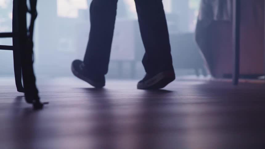 Someone wearing shoes walks on the floor near the furniture
