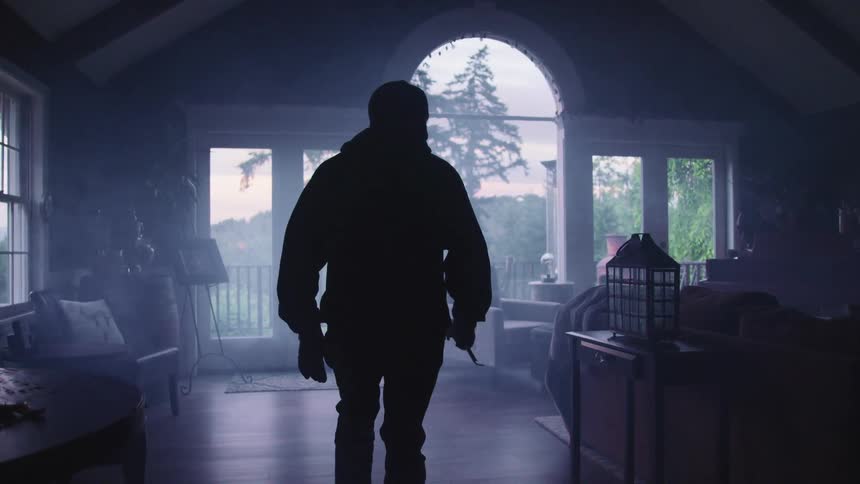 A shadowy man creeps through a house that he has broken into