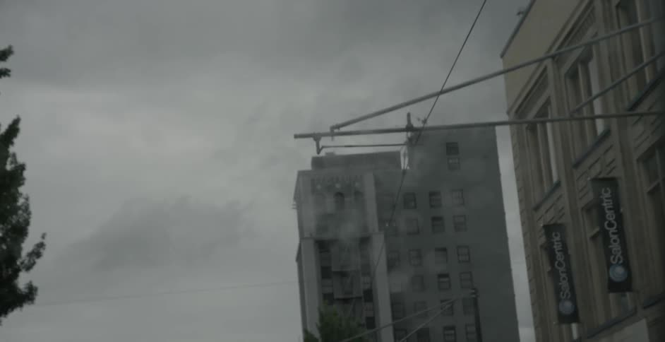 A vehicle drives down a city street on a rainy day