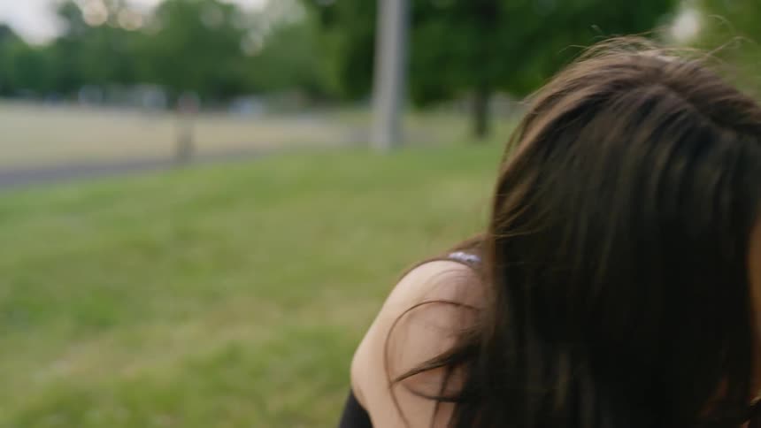 A girl sits near the track and takes off her mask