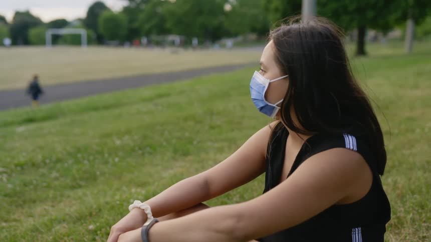 A girl sits on the hill near the track looking around