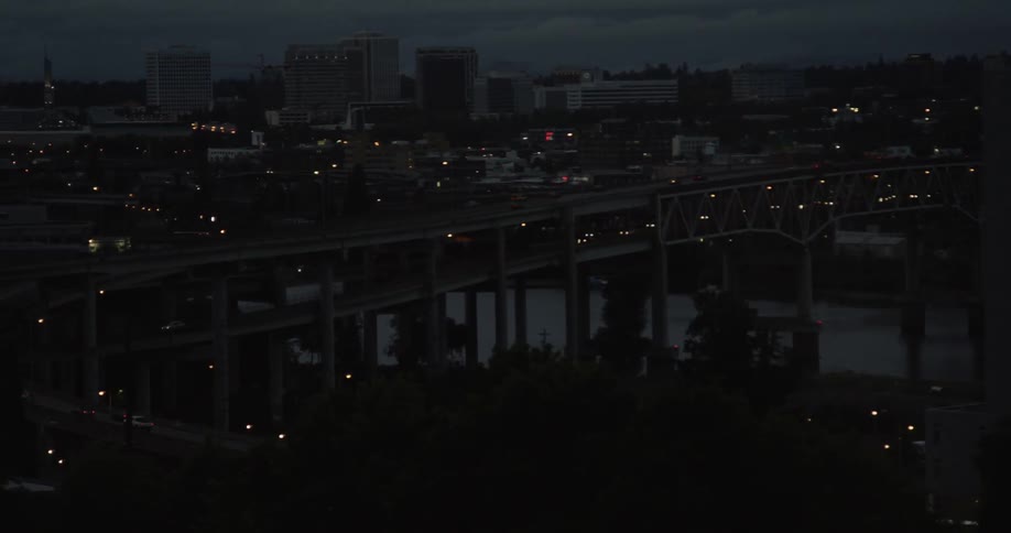 Cars drive across a city bridge at night