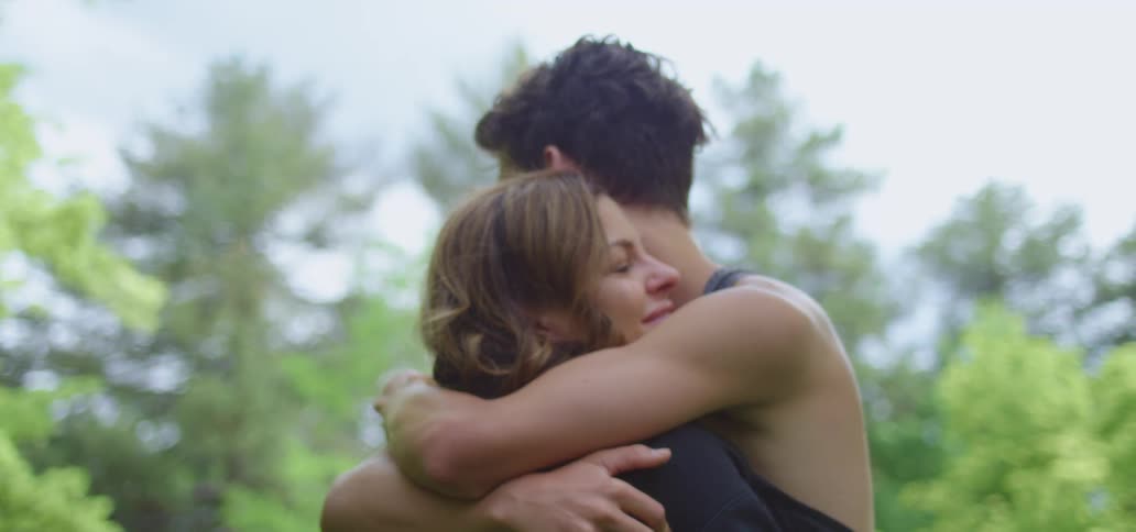 Young couple hug each other near the pine trees in a forest