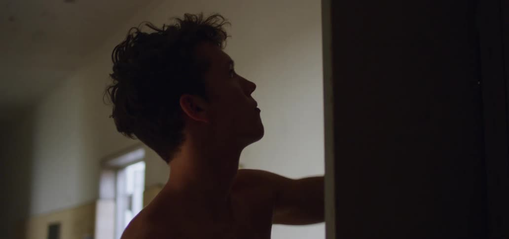 Shirtless young man takes a towel from a closet and heads for the shower