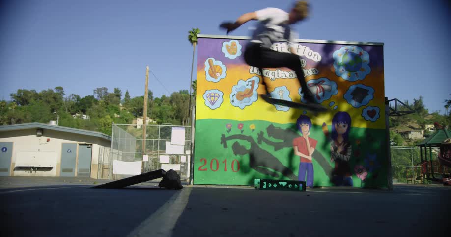 A skateboarder jumps over a small ramp
