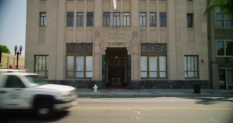 Vehicles drive on a highway road passing by santa ana city hall