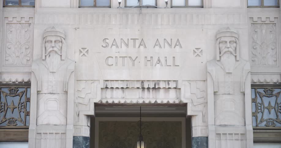 The facade of a city hall with artwork carved into it during the day