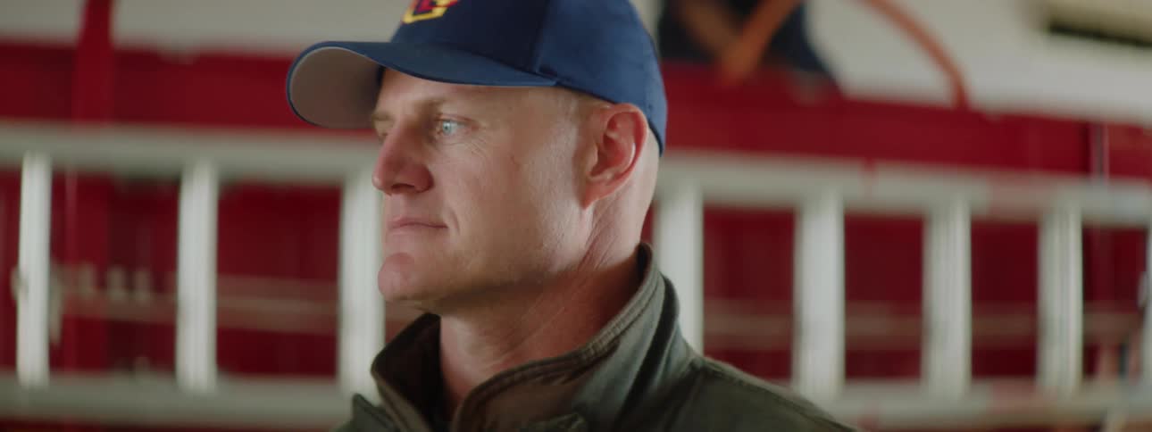 Firefighter stands in front of a red fire truck inside a fire station