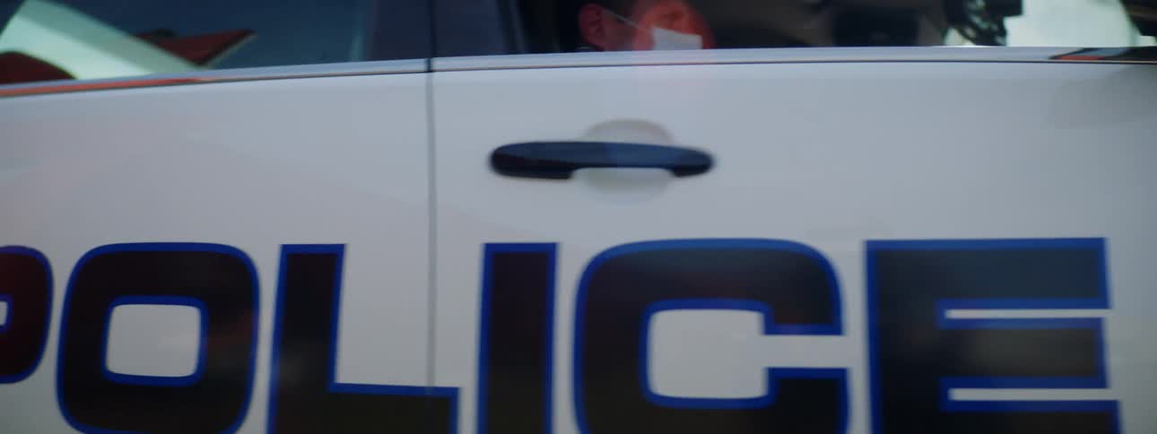 A police car drives down the street of a small town with its siren flashing