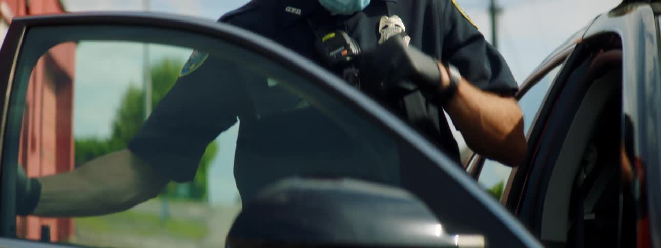 A police officer puts on a mask and gets in his squad car