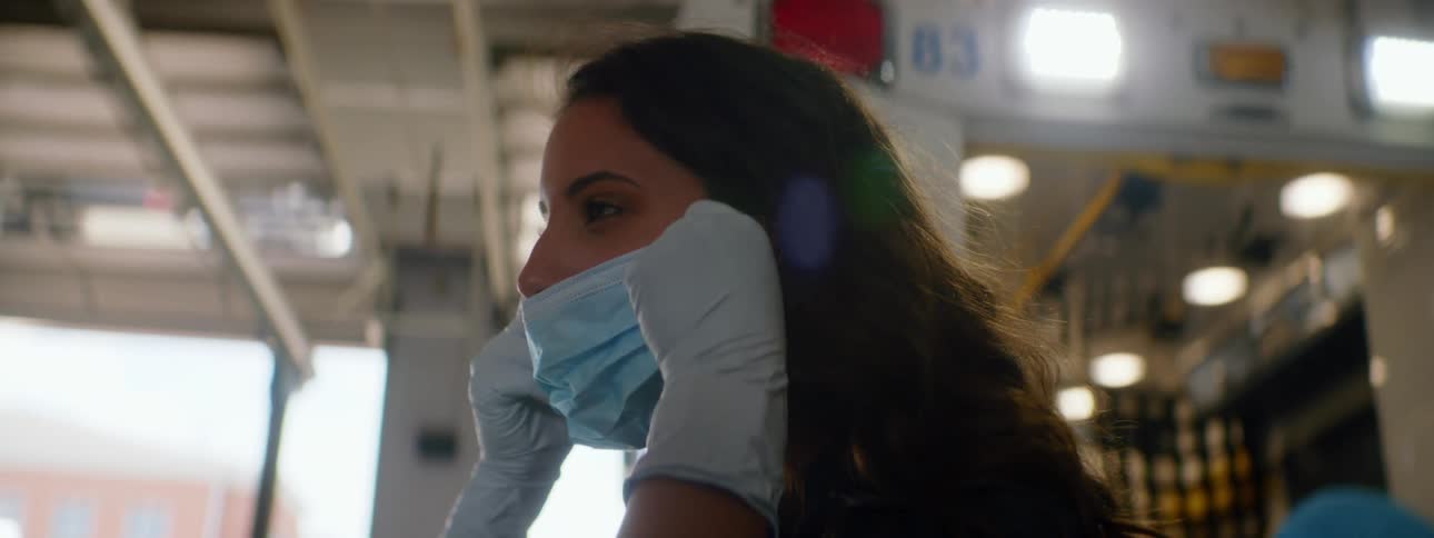 A woman in front of an ambulance puts a mask on