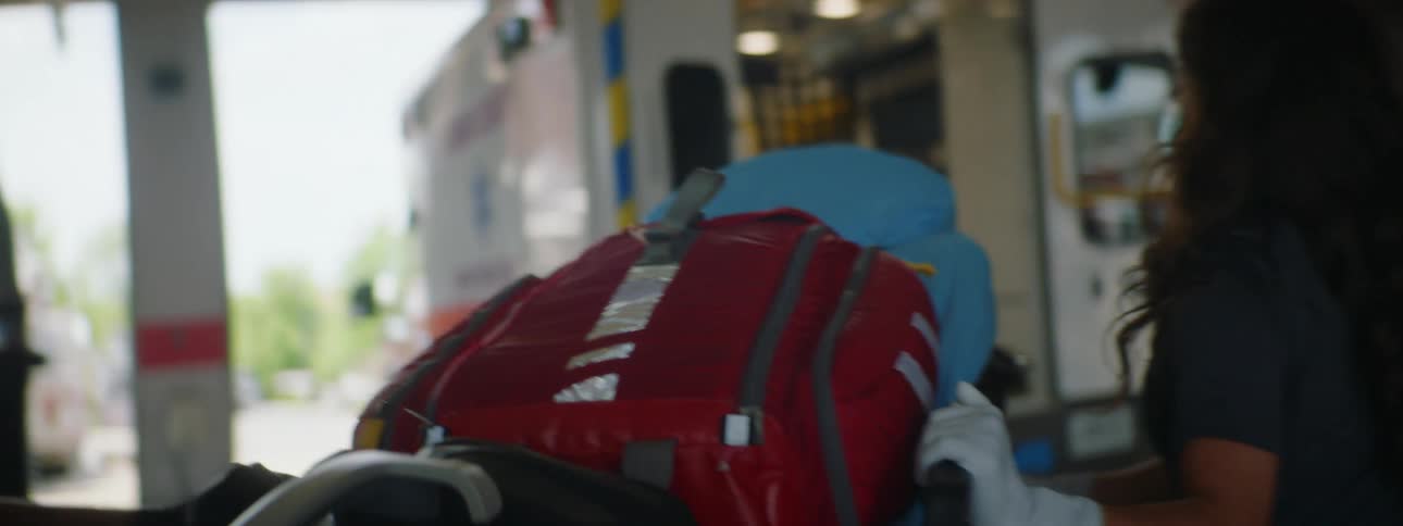 Two medical technicians push a gurney to their ambulance