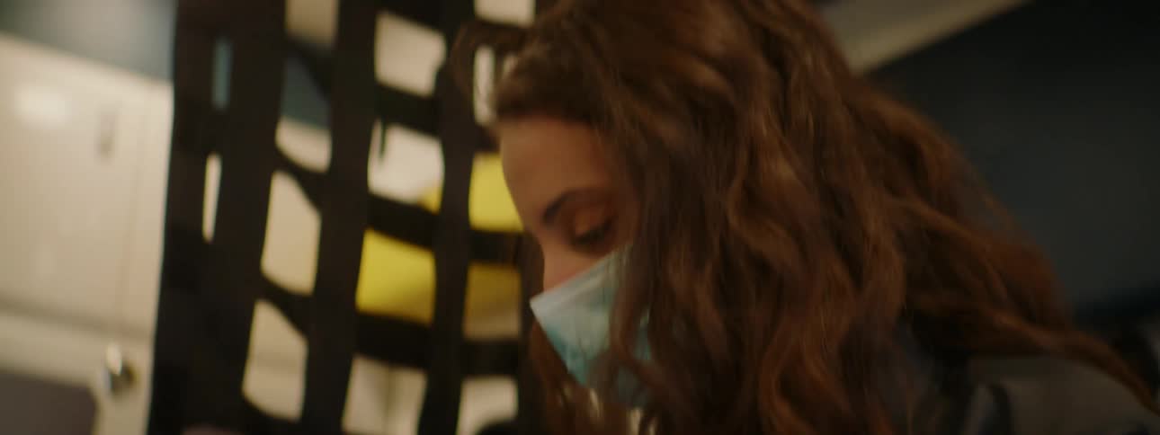 Paramedic wearing face mask and gloves uses a laptop inside an ambulance