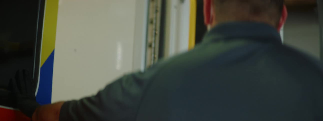 Paramedics wearing gloves and face masks get out of an ambulance and closes the doors