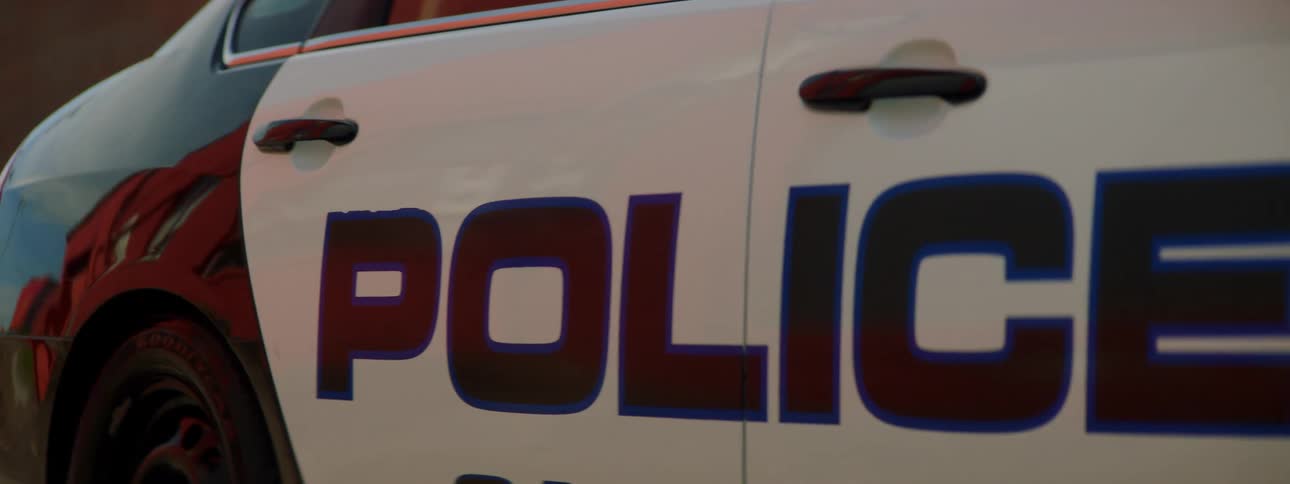 A police car pulls out of a the parking lot of a police station