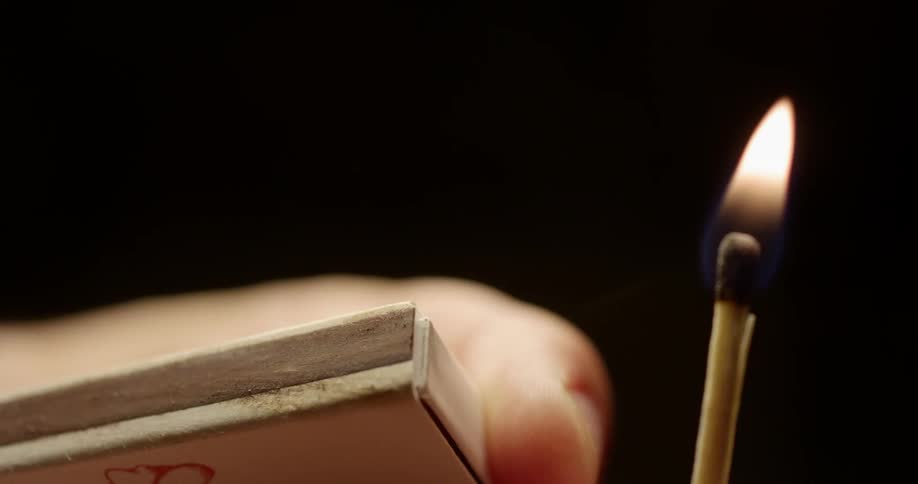 Person striking a match and holding it as it burns