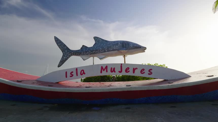 A sign and shark statue on an island