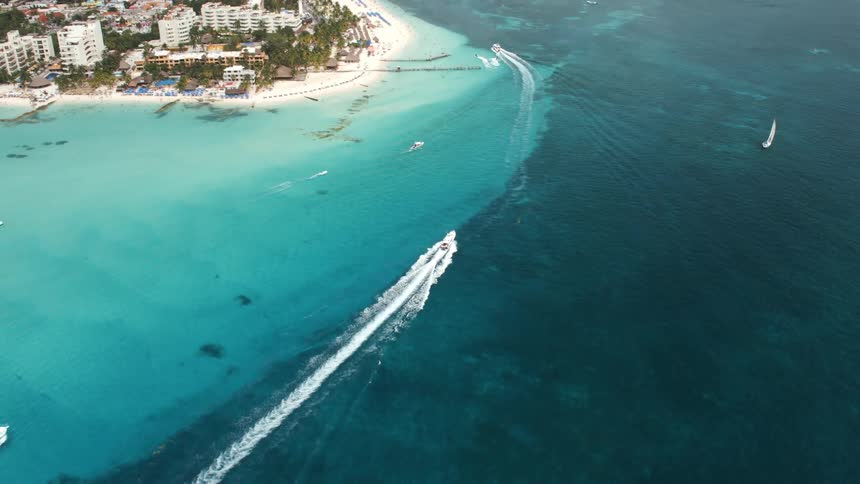 Boats travel in the blue ocean near the shoreline