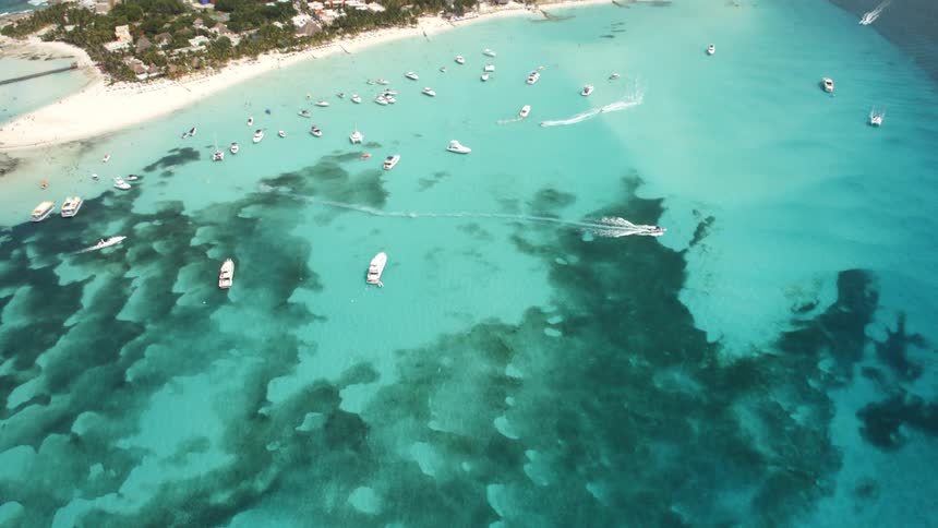 Boats sail off an island coast on turquoise ocean waters