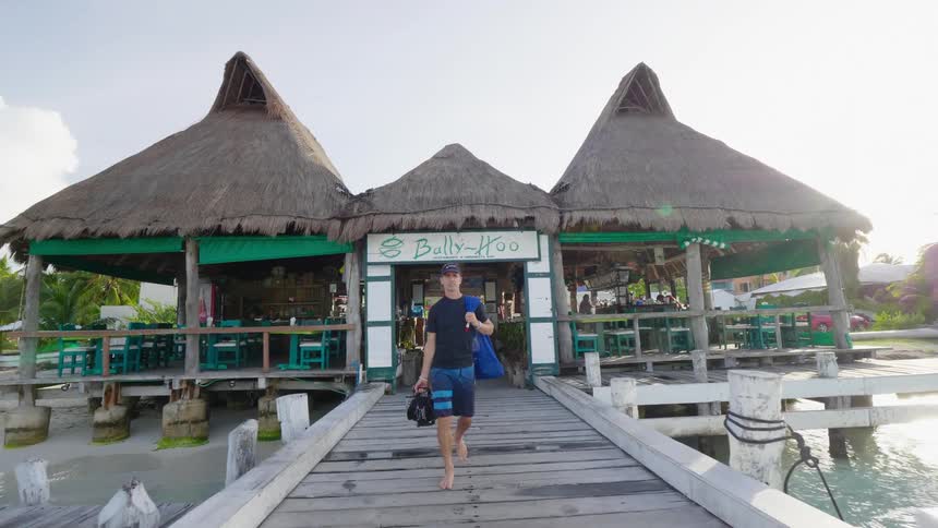 A man is walking out of a store thats located on the beach