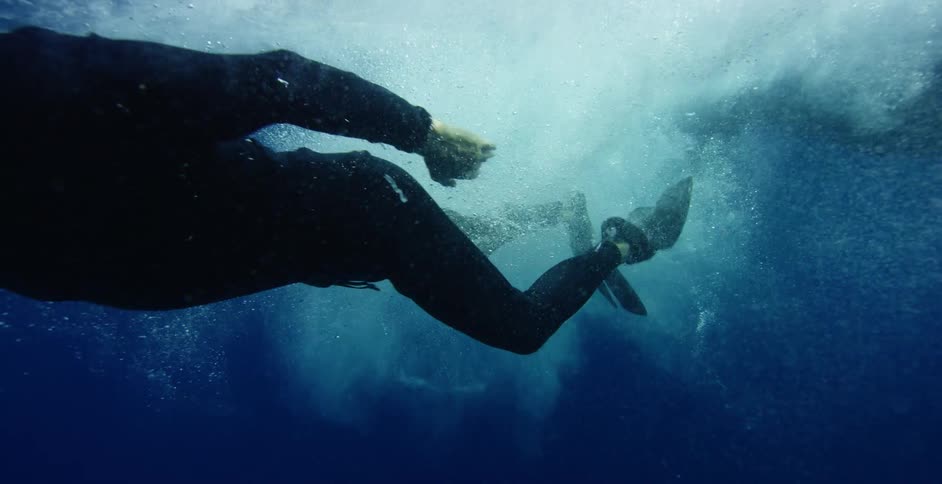A diver jumps in the water with a camera