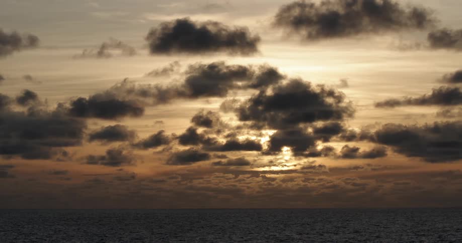 Sunlight filtering through the clouds over the ocean at sunset