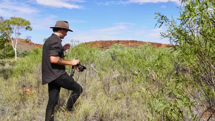 A man is outdoors and taking pictures of nature