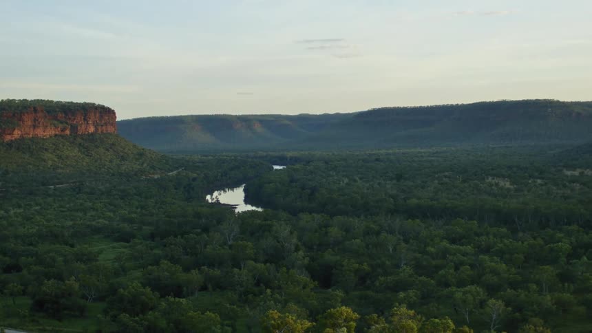 A river through a vast forest beneath high escarpments