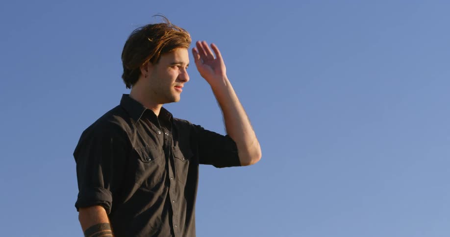 A man guards his eyes from the sun