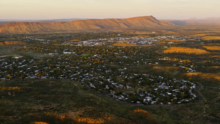 Aerial view of a small town near to a flat mountain range at sunset