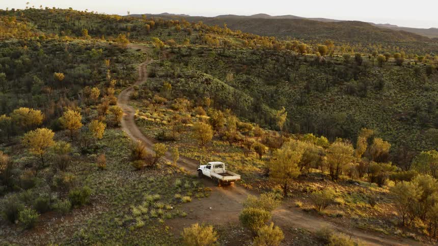 White truck driving on dirt road through the hills in the country