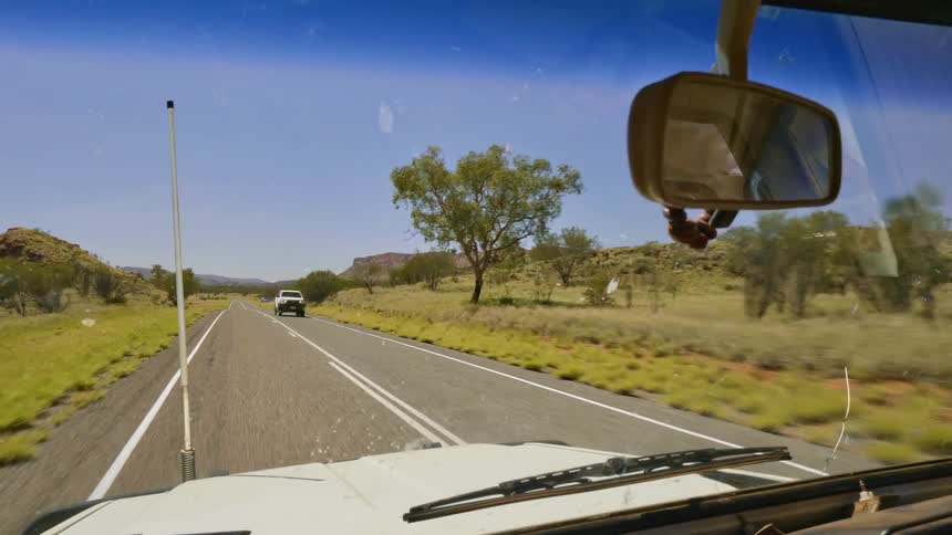 Vehicle travels down the highway past the trees as a truck passes in the opposite direction