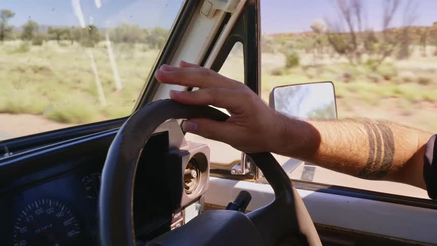 A man is driving past the desert