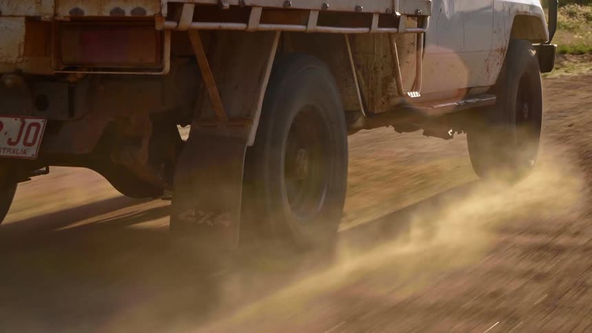 A truck is driving on a dirt trail