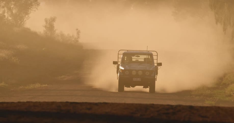 Vehicle travels on a dirt road as it stirs up dust